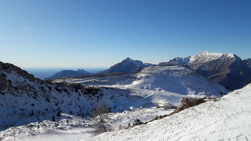 Panoramic view of snowcapped mountains against clear blue sky