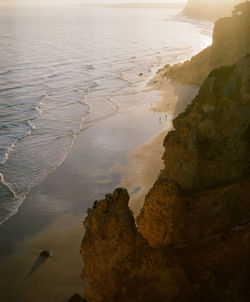 Rock formation on beach against sky during sunset