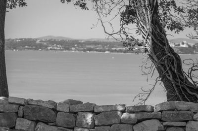 Stone wall by sea against sky