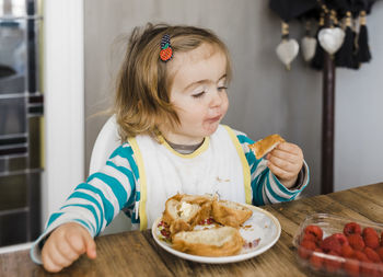 Cute girl eating food on table