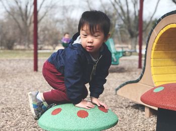 Portrait of cute boy playing on outdoor play equipment in playground