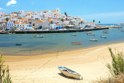 Sailboats moored on beach against buildings in city