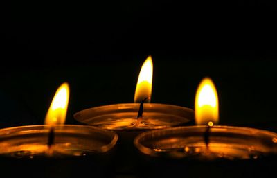 Close-up of illuminated tea light candles against black background