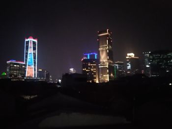 Illuminated buildings against clear sky at night