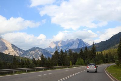 Cars on road by mountains against sky