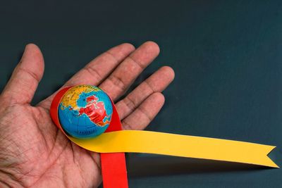 Cropped hand holding globe and ribbon