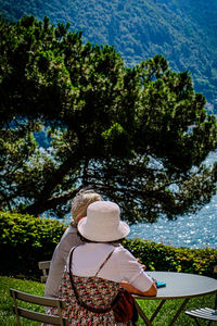 Rear view of woman sitting by lake