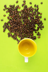 Coffee beans on a yellow surface and a colored cup