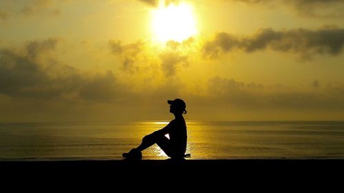 Silhouette man on beach against sky during sunset