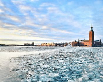 Scenic view of sea by buildings against sky during winter