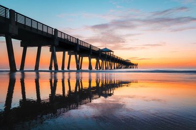 Pier on sea against sky at sunset