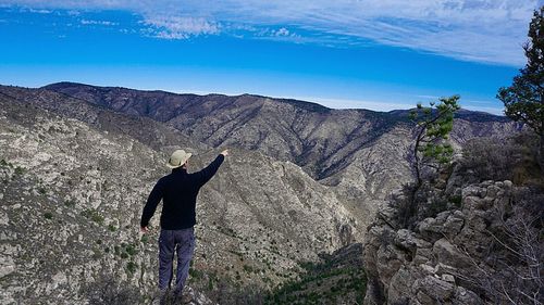 Rear view of man on mountain against sky