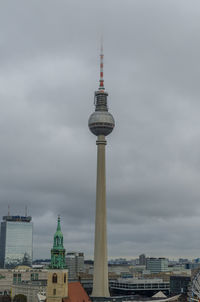 Tower in city against cloudy sky