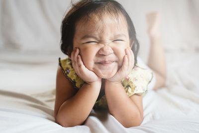 Cute baby girl lying on bed at home