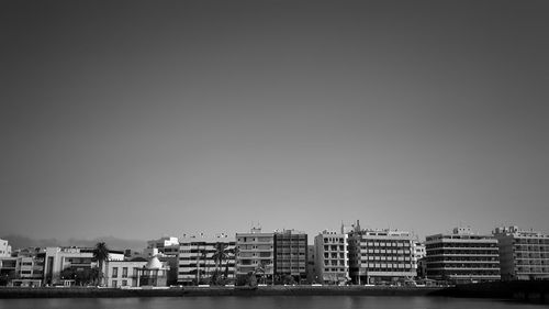 Cityscape by sea against clear sky