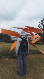 Rear view of man standing on field against sky