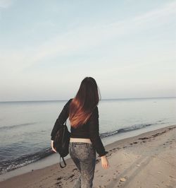 Rear view of woman walking at beach