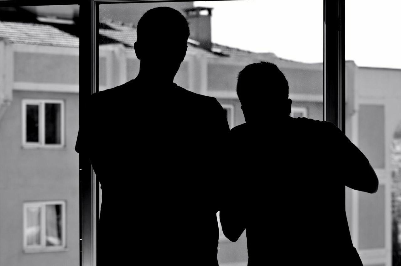 two people, men, real people, silhouette, rear view, togetherness, indoors, love, standing, window, built structure, leisure activity, childhood, bonding, lifestyles, boys, day, friendship, architecture, people