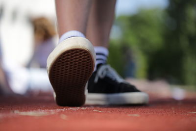 Low section of man tying shoelace on field