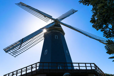 Low angle view of traditional windmill against clear blue sky