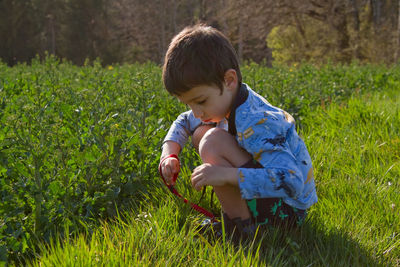 Side view of boy sitting on field