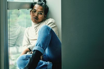 Portrait of man sitting on window sill