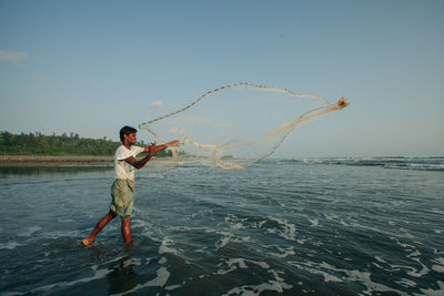 Full length of man holding sea against clear sky