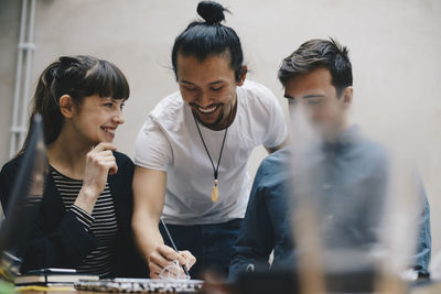 Happy computer programmer writing while discussing with colleagues in office