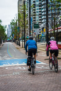 Rear view of man riding bicycle on building in city