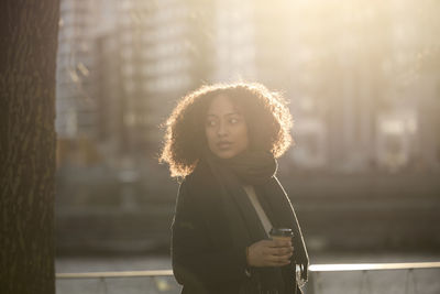 Beautiful woman with takeaway coffee posing on street