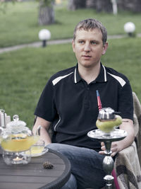 Young man holding hookah by table at courtyard