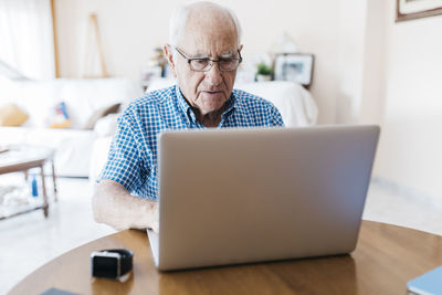 Porrtait of senior man at home learning to use laptop