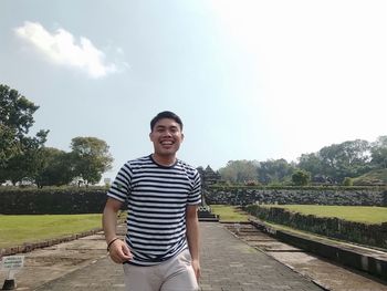 Portrait of smiling young man standing against sky