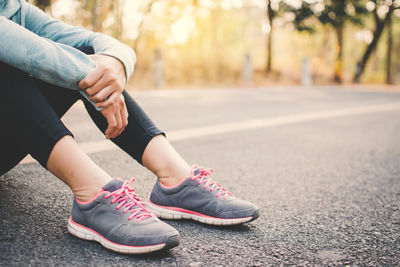 Low section of woman sitting on road