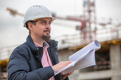 Young man looking away at construction site