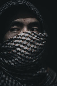 Close-up portrait of man wearing mask against black background