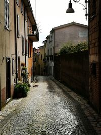 Walkway amidst buildings against sky