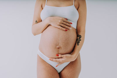 Midsection of sensuous woman standing against white background