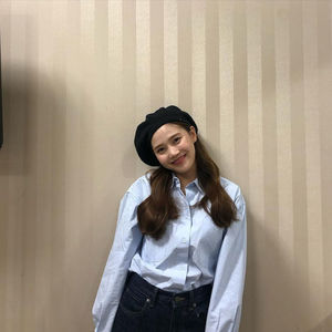 Portrait of smiling young woman standing against wall