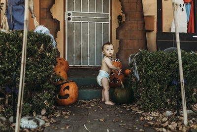 Baby toddler boy in diaper with halloween decorations during fall