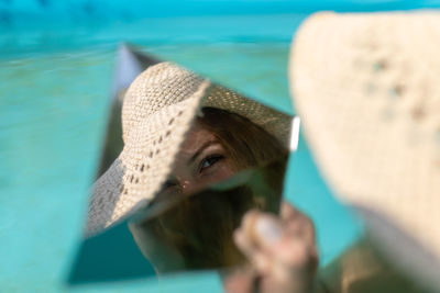 Reflection of woman in mirror while sitting in swimming pool