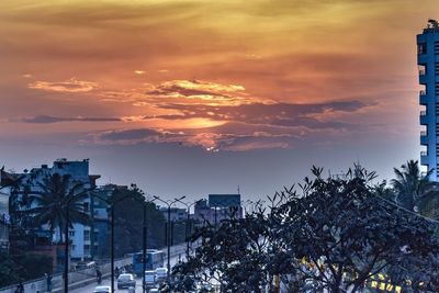 Silhouette of buildings against cloudy sky during sunset