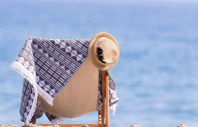 Sun hat with towel on empty deck chair at beach