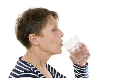 Midsection of man drinking glass against white background