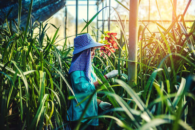 Side view of female researcher examining plants in greenhouse