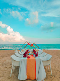 Chairs and table at beach against sky