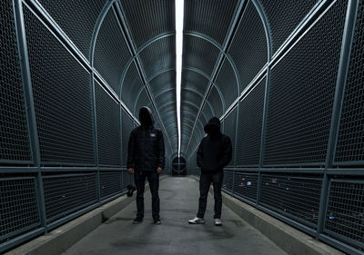 Low angle view of men standing on bridge walkway at night