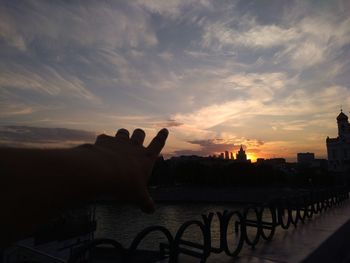 Person holding hands against sky during sunset