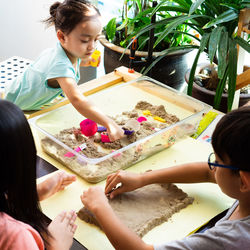 High angle view of siblings playing with sand