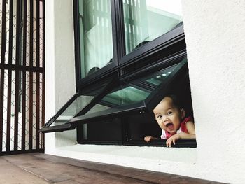 Cute surprised baby girl screaming while looking through window